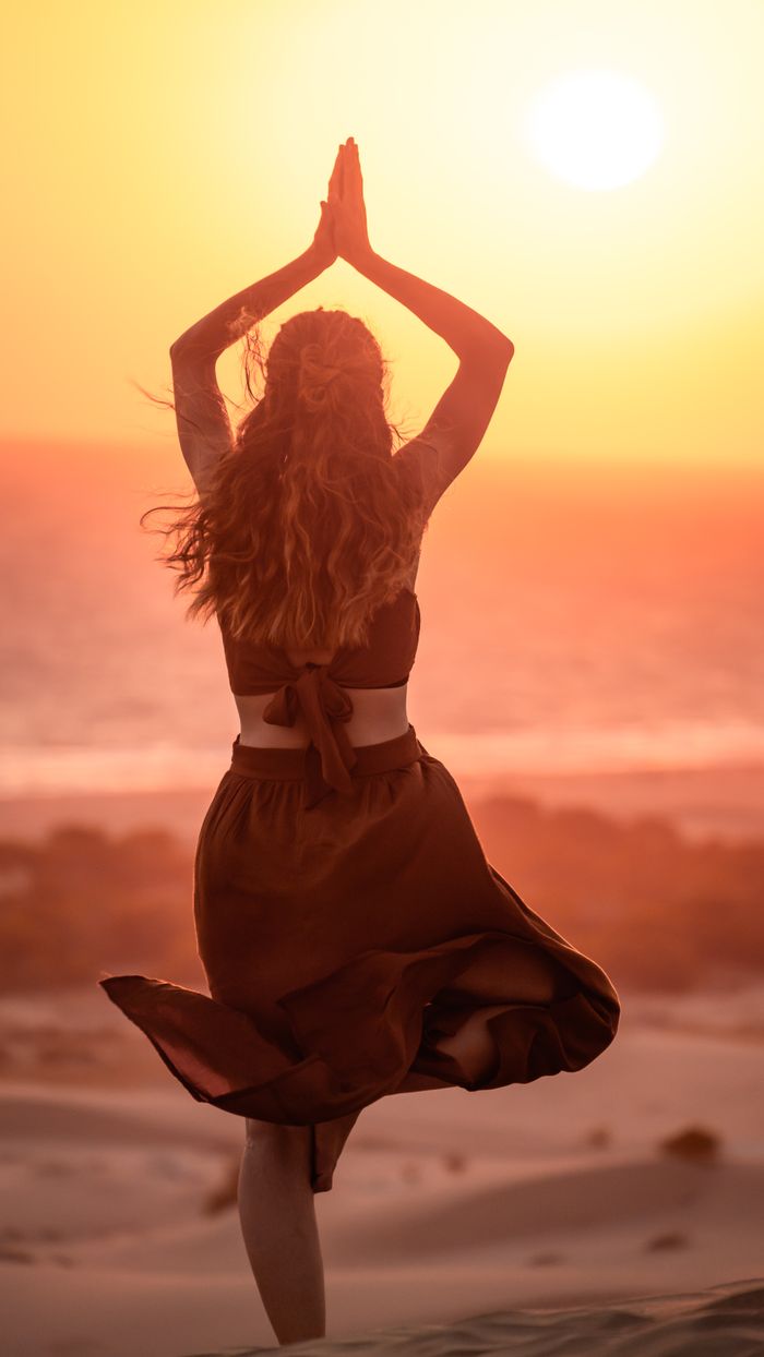services-img Serene scene of a woman performing yoga during sunset on Antalya's beach with a warm glow.
